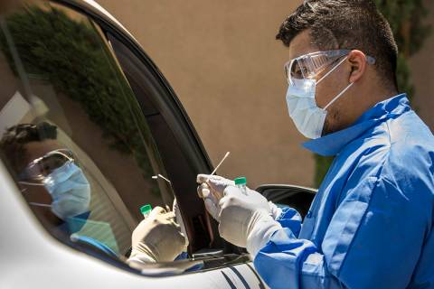 Practice Manager Jose Tirana conducts a COVID-19 test on a patient in the parking lot at Sahara ...