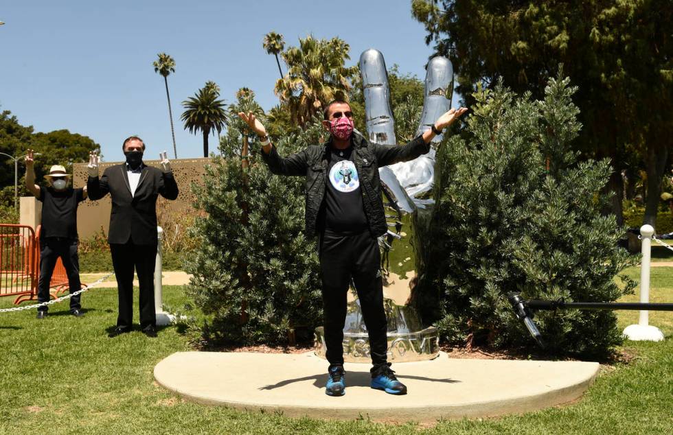 Musician Ringo Starr poses in front of his "Peace and Love" sculpture on his 80th bir ...