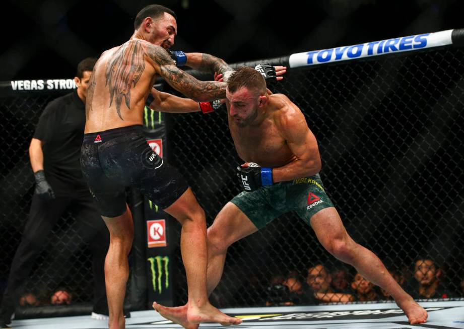 Max Holloway, left, fights Alexander Volkanovski during their featherweight title boutÊin UFC ...