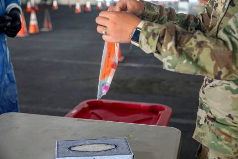 A Nevada National Guardsmen combat medic seals a plastic bag with a COVID-19 test used in a dem ...