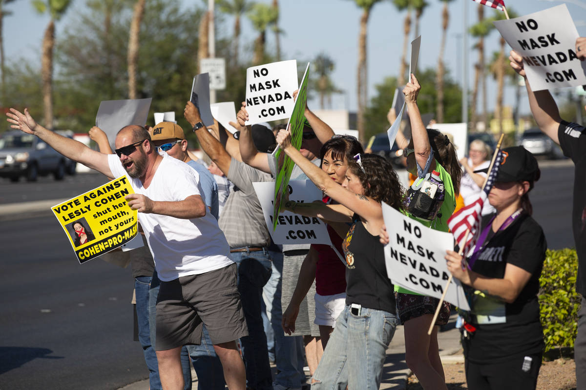 One protester reaches out to passing cars during the "No Mask Protest" at the interse ...