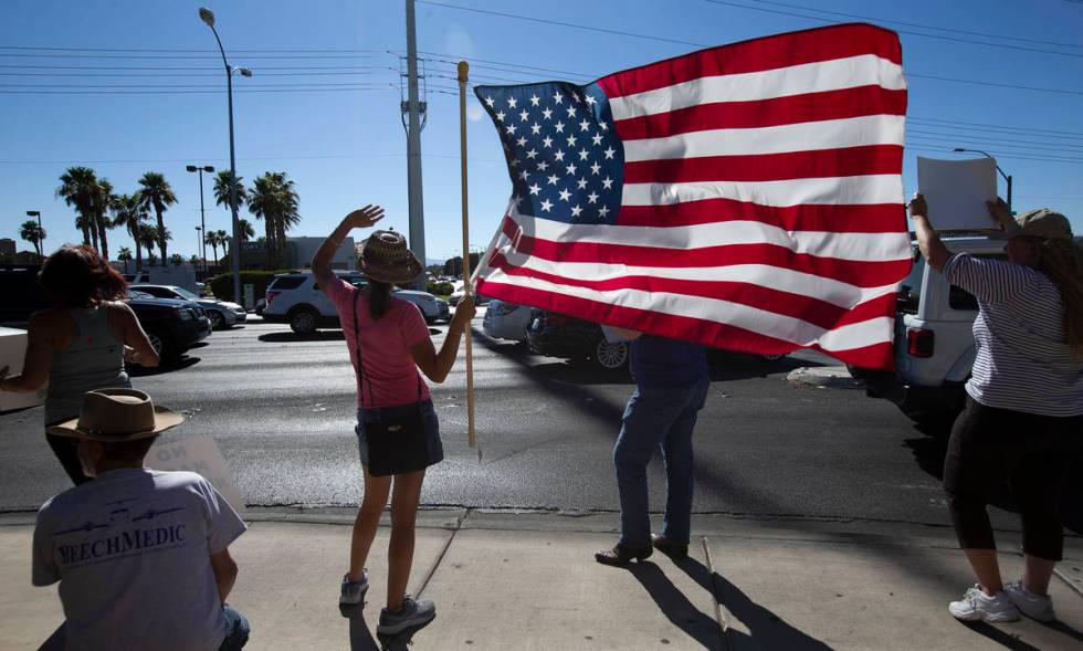 Faith Muello, second from left, holds an American Flag at the "No Mask Protest" at th ...