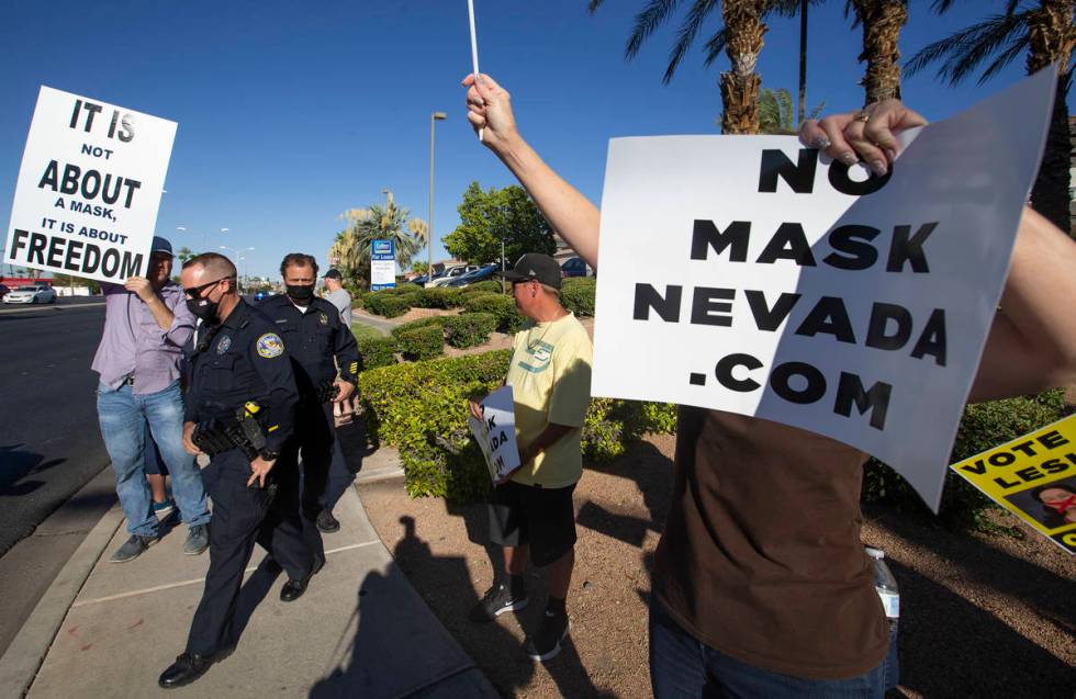 Metropolitan police donned masks as they spoke with protesters at the "No Mask Protest&quo ...