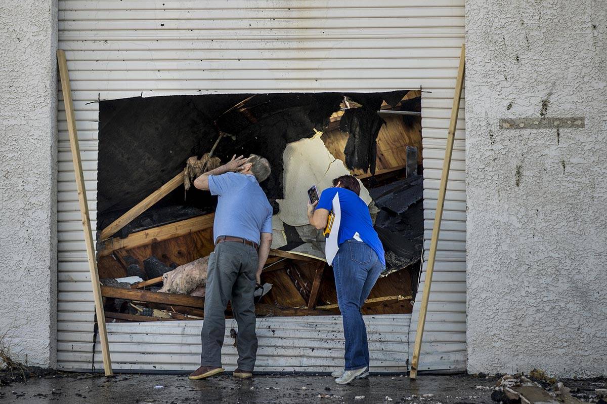 People inspect the damage from an early morning a two-alarm fire in a commercial structure near ...