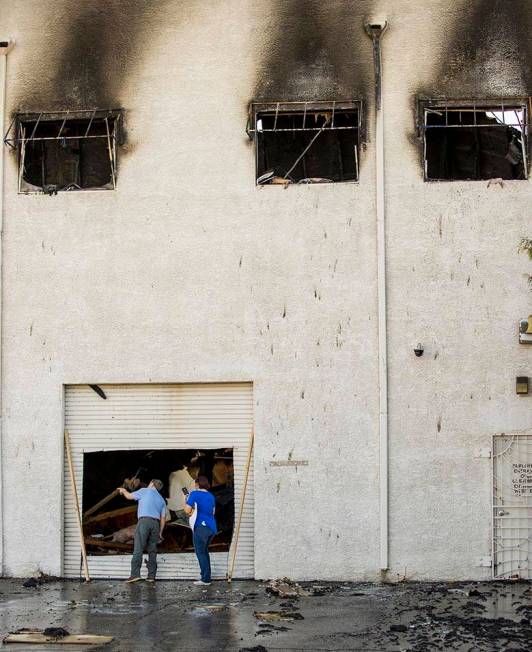 People inspect the damage from an early morning a two-alarm fire in a commercial structure near ...