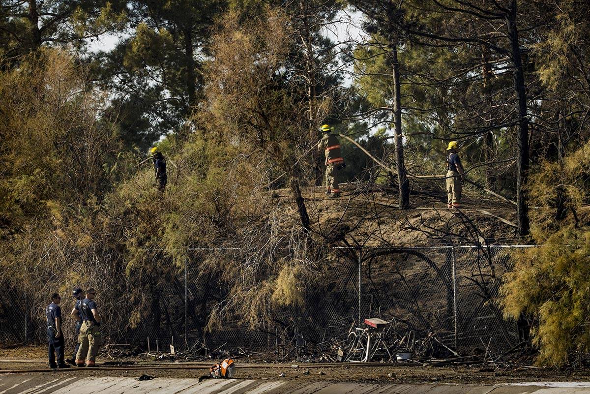 A homeless encampment is burned down as Clark County firefighters extinguish a brush fire in ea ...