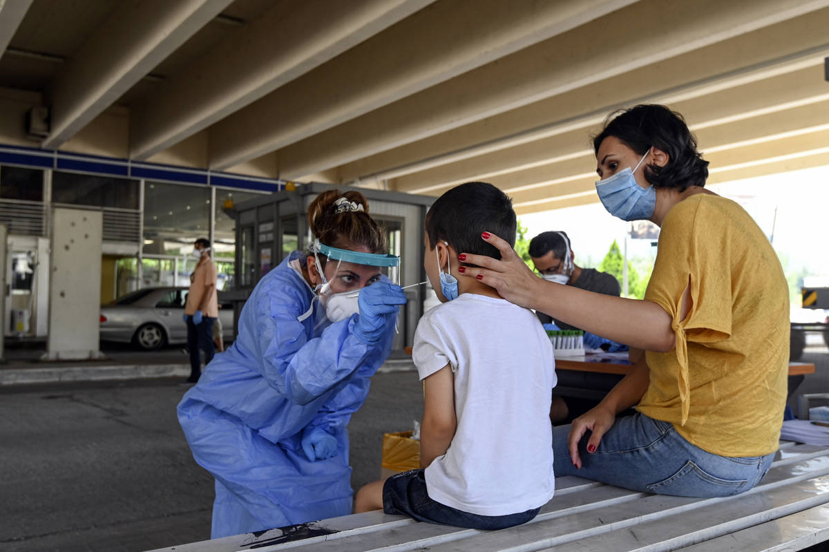 A health worker wearing protective gear takes swab samples from tourists to test for the corona ...
