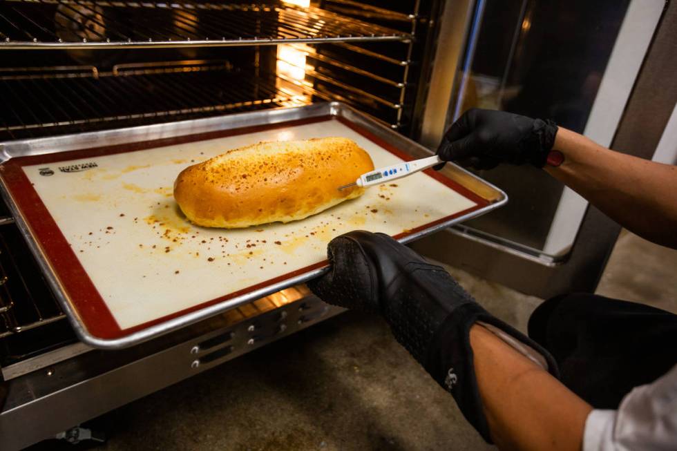 Jorge Padilla, pastry chef assistant, checks the internal temperature of a loaf of Columbian ch ...