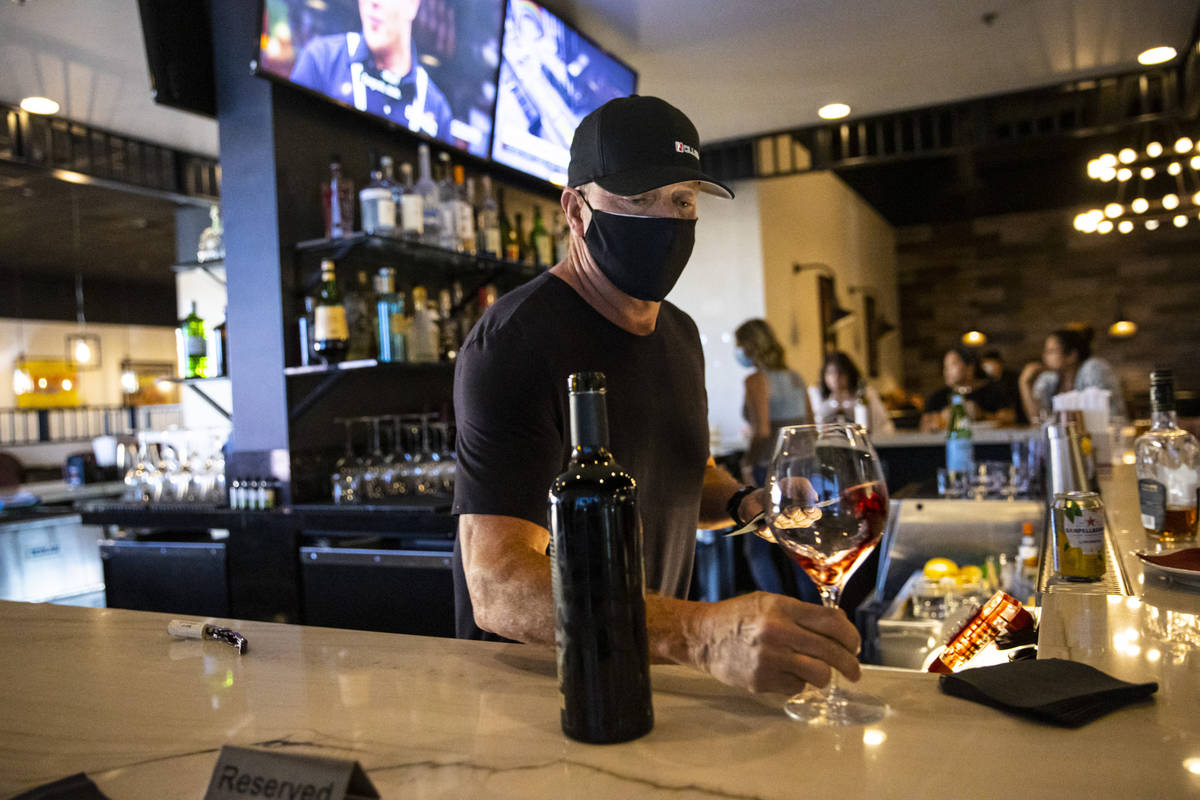 Bar manager David Cooper prepares a glass of wine for Marti Taylor, not pictured, during happy ...