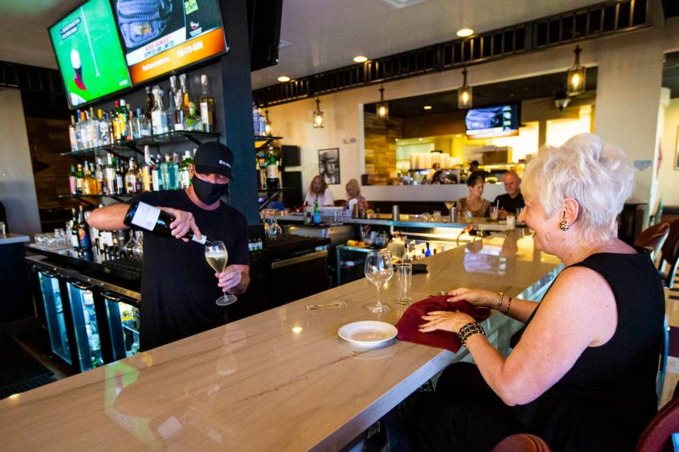 Bar manager David Cooper pours a drink for Dale Robins, of Las Vegas, during happy hour at Spag ...