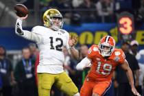 Notre Dame quarterback Ian Book (12) throws a pass under pressure from Clemson safety Tanner Mu ...