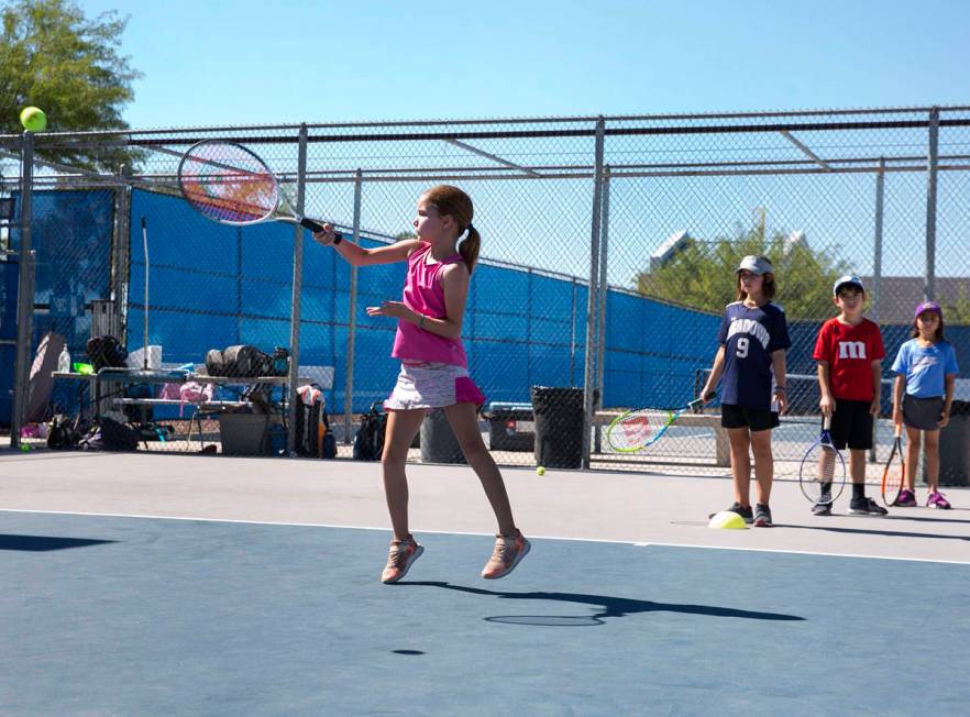 Jemma Michael, 7, returns the ball as she plays tennis at Camp Mustang at The Meadows School on ...