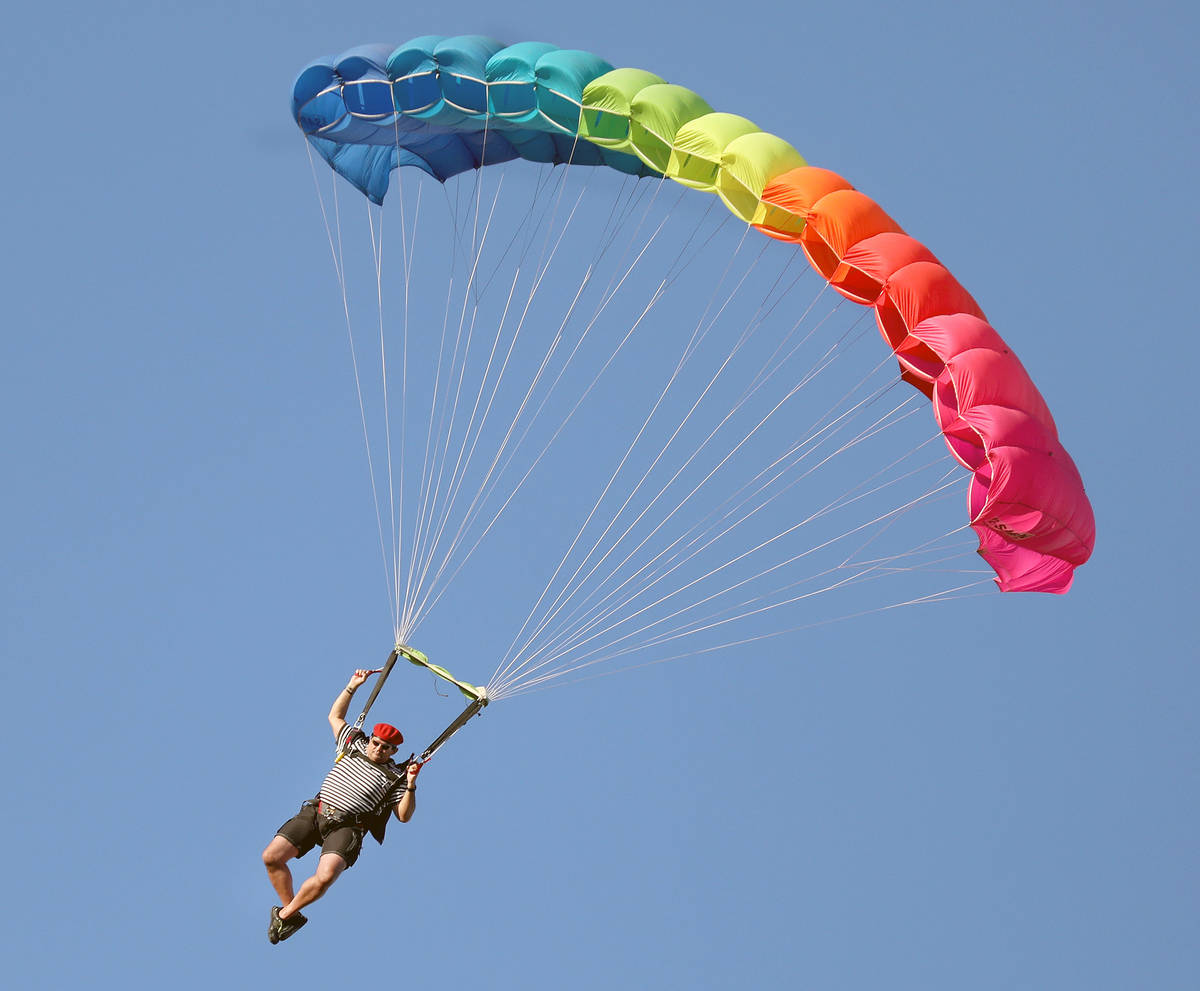 A skydiver descends from a plane for Marché Bacchus' Bastille Day celebration, in front of the ...