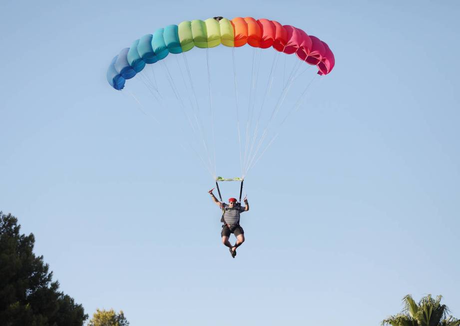 A skydiver descends from a plane for Marché Bacchus' Bastille Day celebration, in front of the ...