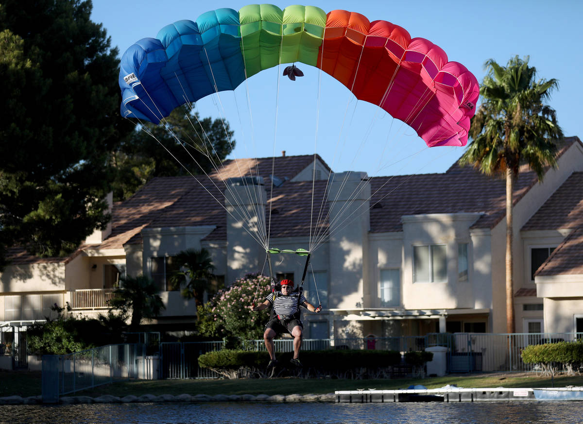 A skydiver descends from a plane for Marché Bacchus' Bastille Day celebration, in front of the ...