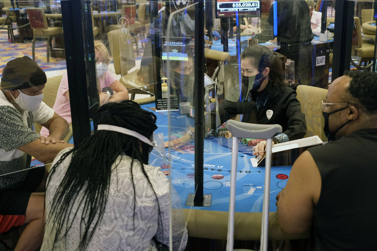 Partitions between players and face masks allow gamblers to enjoy card games at the Hard Rock C ...