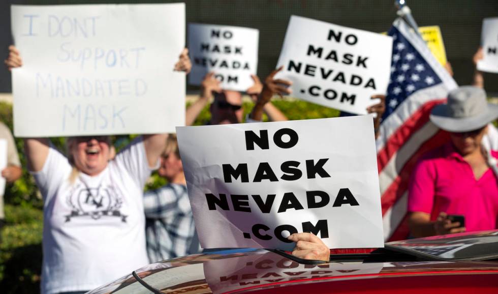 A passing car supports the "No Mask Protest" at the intersection of West Sunset Road ...