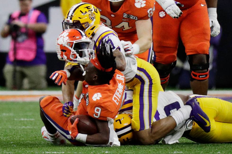 LSU safety Grant Delpit knocks the helmet off Clemson running back Travis Etienne during the fi ...