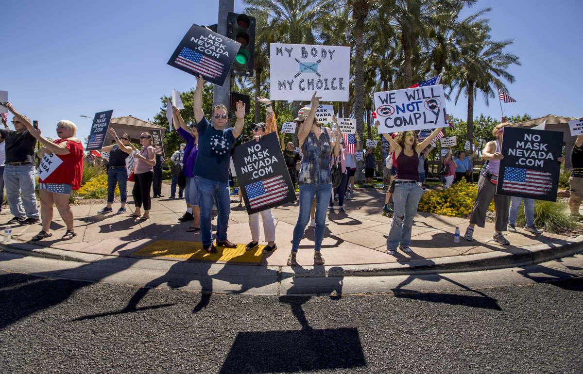 Protesters hold signs and chant slogans during a No Mask Nevada PAC rally along South Green Val ...