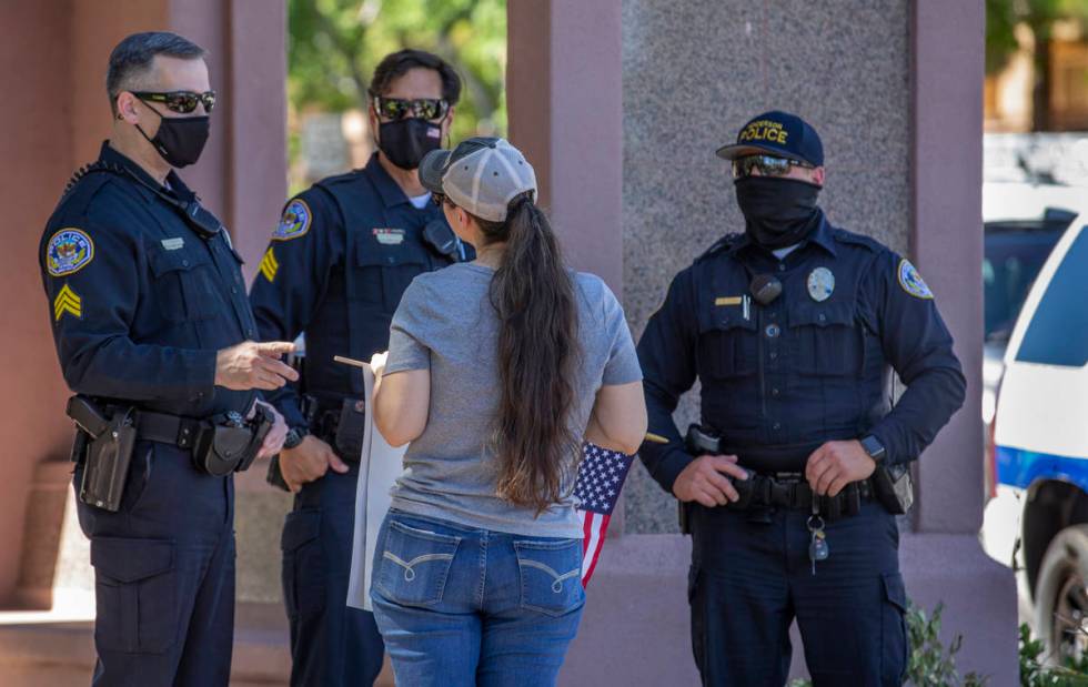 Henderson police officers speak with a protester during a No Mask Nevada PAC rally along South ...
