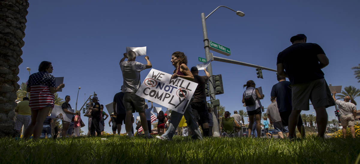 Protesters hold signs and chant slogans during a No Mask Nevada PAC rally along South Green Val ...