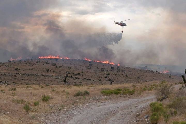 A helicopter is used to battle flames at the Cottonwood Fire north of Goodsprings and southwest ...