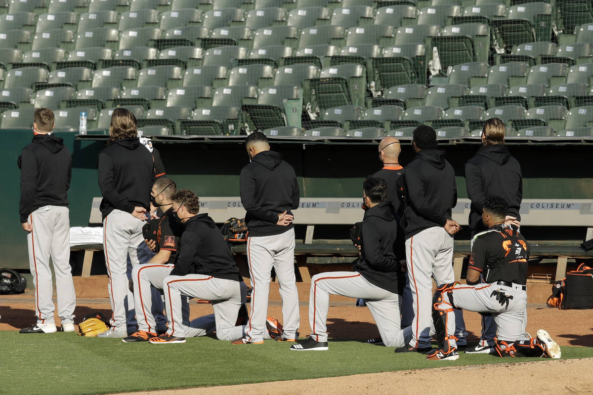 Some San Francisco Giants kneel during the national anthem prior to an exhibition baseball game ...