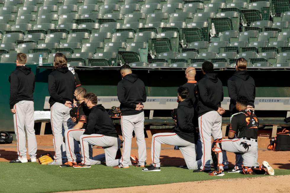 Some San Francisco Giants kneel during the national anthem prior to an exhibition baseball game ...