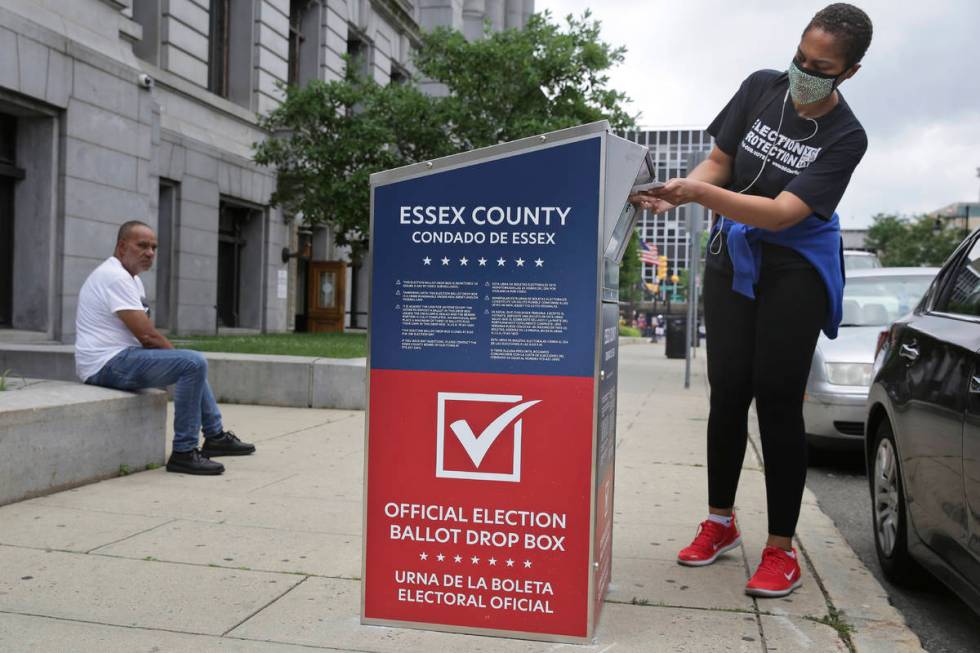 A woman drops her mail-in ballot into a drop box in Newark, N.J., Tuesday, July 7, 2020. New Je ...