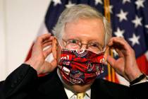 Senate Majority Leader Mitch McConnell of Ky., replaces his face mask after speaking at news co ...