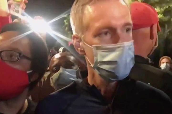 In this image made from video released by Karina Brown, Portland Mayor Ted Wheeler, right, stan ...