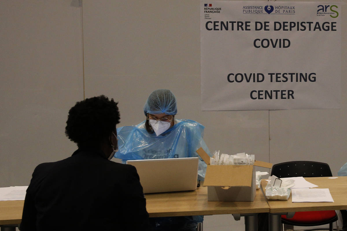 Medical staff take charge of passengers in a COVID-19 testing center, set up in the arrival hal ...