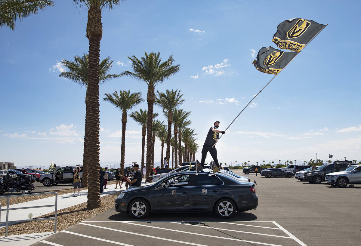 Matt Helfst waves a flag as he waits for the Golden Knights players to pass in buses as they le ...