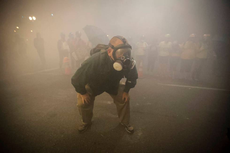 A demonstrator wears a gas mask as federal officers deploy tear gas during a Black Lives Matter ...