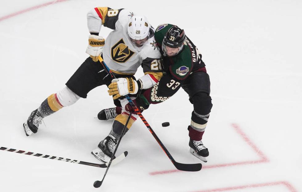 Arizona Coyotes' Alex Goligoski (33) and Vegas Golden Knights' William Carrier (28) battle for ...