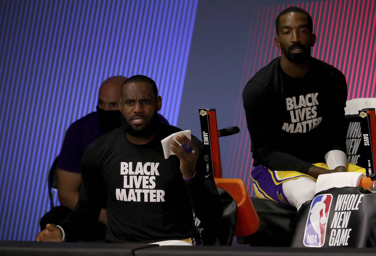 Los Angeles Lakers' LeBron James, front left, and JR Smith, right, look on from the bench duri ...