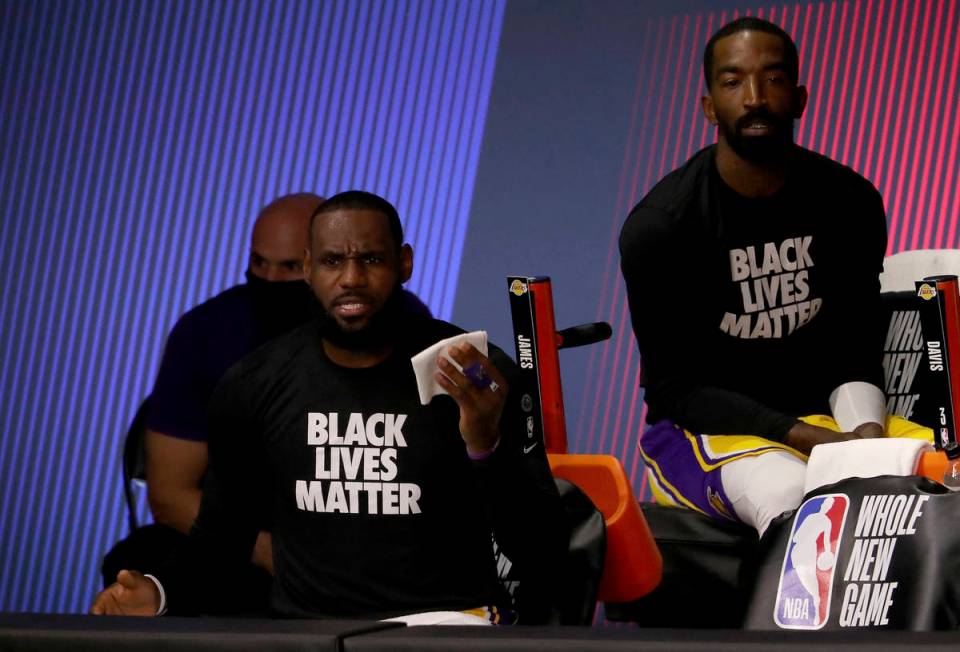 Los Angeles Lakers' LeBron James, front left, and JR Smith, right, look on from the bench duri ...