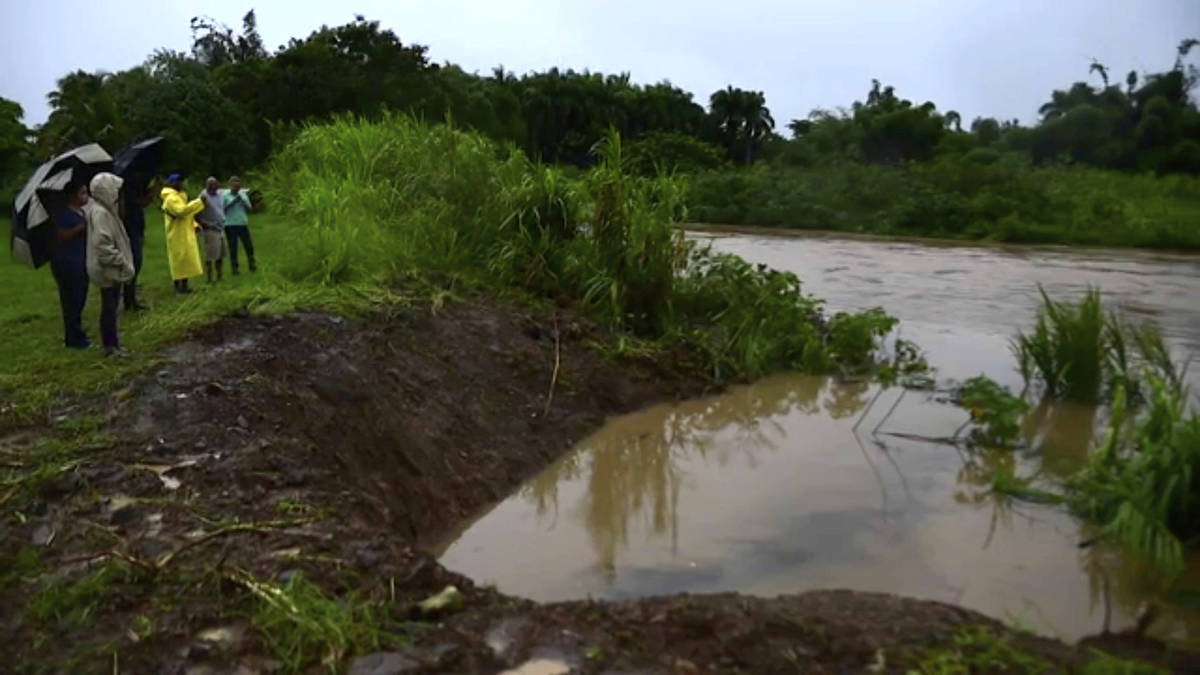 In this image made from video, people look at level of Canovanas river following heavy rain cau ...