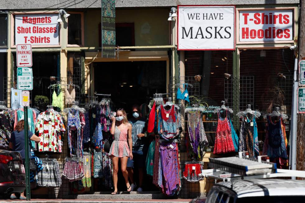 Shoppers leave a clothing shop that now also sells masks to help fight the spread of the corona ...