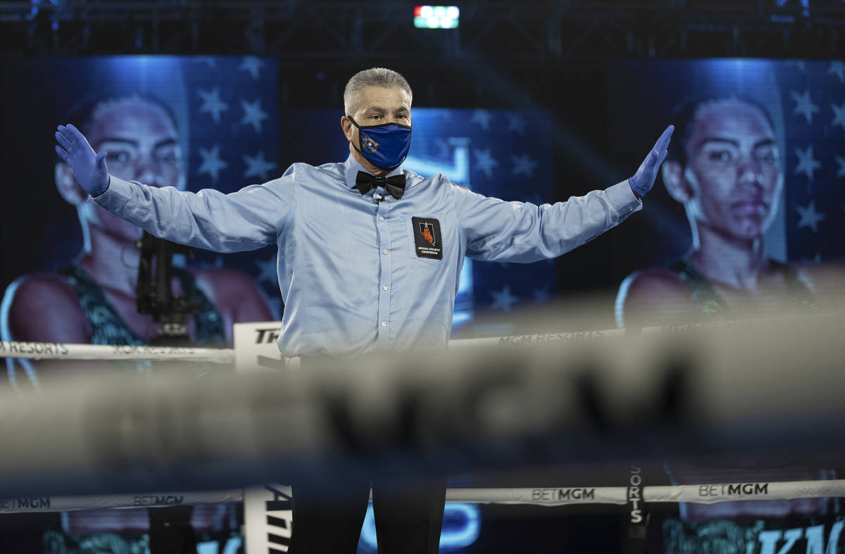 A referee holds both fighters in their corner before the start of a round during Top Rank boxin ...