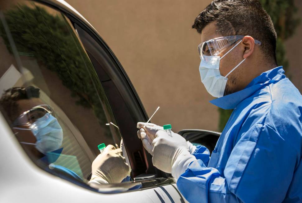 Practice Manager Jose Tirana conducts a COVID-19 test on a patient in the parking lot at Sahara ...