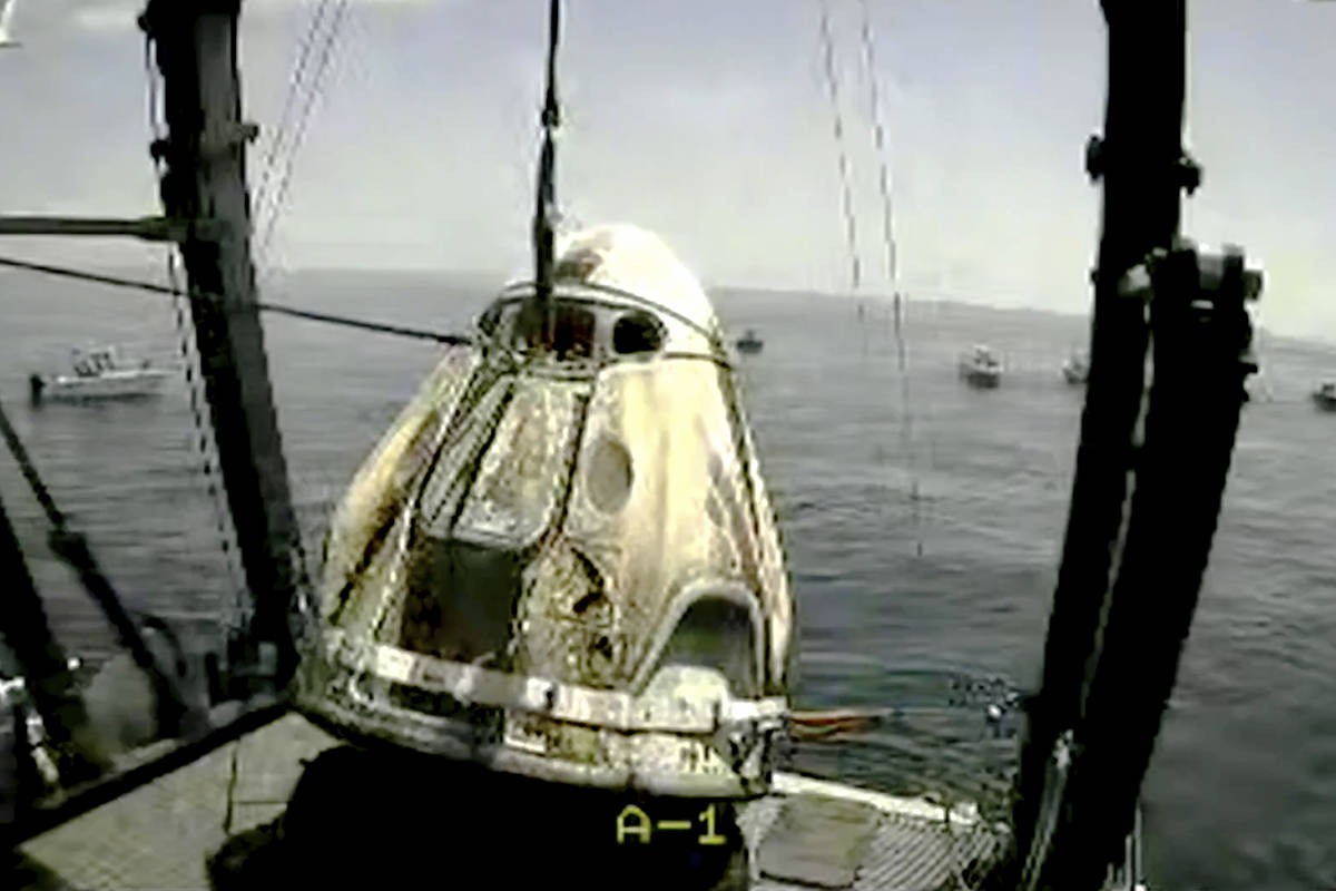 In this frame grab from NASA TV, the SpaceX capsule is lifted onto a ship, Sunday, Aug. 2, 2020 ...