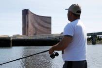 A man fishes in the Mystic River in Somerville, Mass., across from Encore Boston Harbor, Wednes ...
