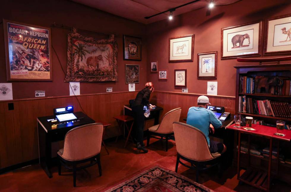 Bartender Silken Widmer sanitizes a gaming device in a lounge area at Black Mountain Grill in H ...