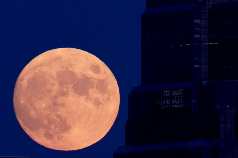 The full moon rises with an office building in the foreground, Sunday, Aug. 2, 2020, in downtow ...