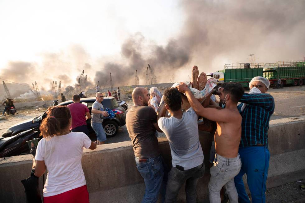 People evacuate wounded after of a massive explosion in Beirut, Lebanon, Tuesday, Aug. 4, 2020. ...