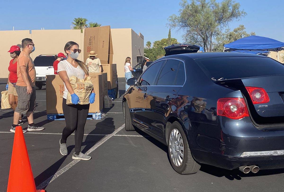 A worker brings food to a car at a food distribution event near North Jones Boulevard and West ...