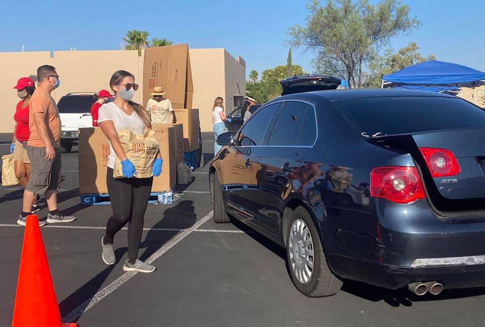 A worker brings food to a car at a food distribution event near North Jones Boulevard and West ...