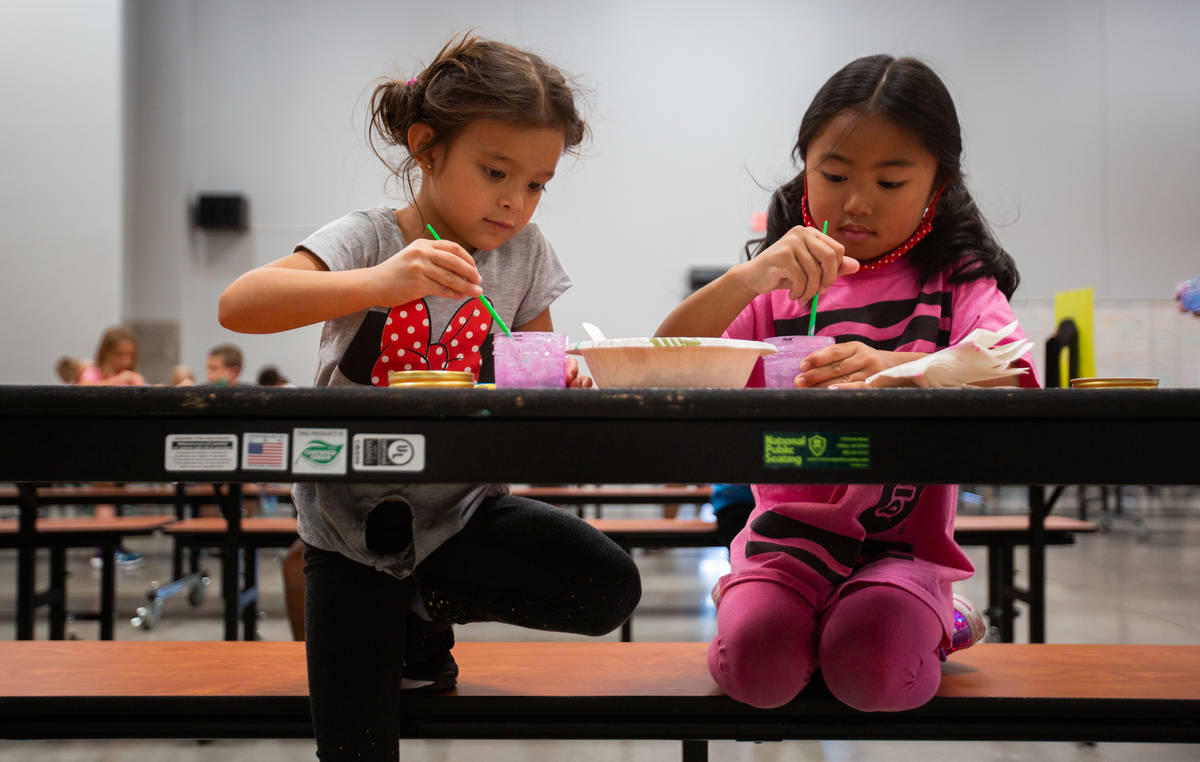 Kylie, 5, left, and Teagan, 5, play with paint in the cafeteria during a summer camp at Legacy ...