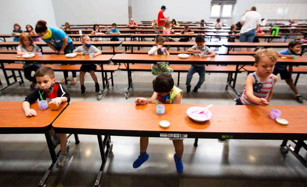 Children play with paint in the cafeteria during a summer camp at Legacy Traditional School in ...